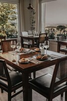 Comedor con mesa de madera dispuesta para dos personas, dos copas de vino y un plato de comida.