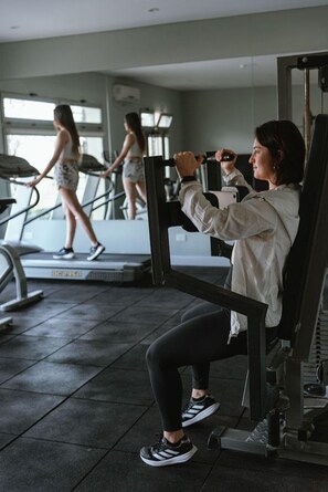 Ein Fitnessraum mit Trainingsgeräten, Laufband und Spiegel.