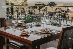 An outdoor dining area with tables set for a meal, surrounded by chairs and plants. - Amaike Hotel Golf and Spa (Tandil)