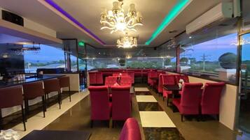 A restaurant with red upholstered booths, a bar area, and a chandelier.