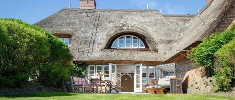 A house with a thatched roof, a large arched window, and a front door.