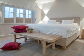 Ein Schlafzimmer mit einem großen Bett, einer Holzbank und einem Fenster mit Jalousien.
