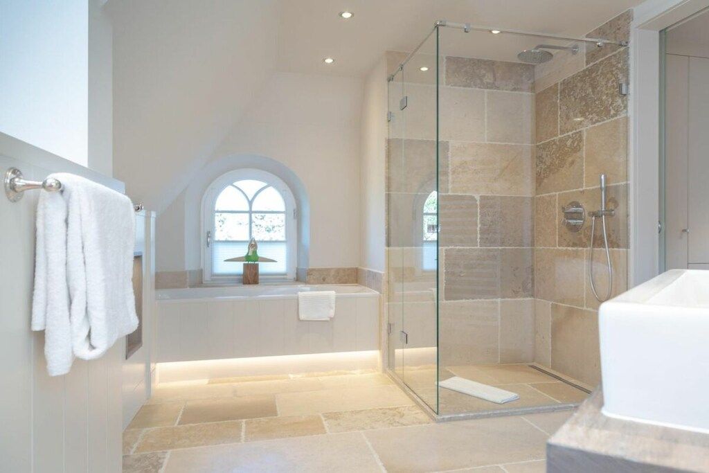 A modern bathroom with a glass-enclosed shower, a bathtub, and a vanity with a mirror.