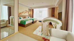 A hotel room with a large mirror, a bed with green bedding, a sofa, a play area, and a television. - Vienna International Hotel (Wuhan)