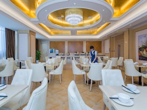 Zona de dinar d'un hotel amb caires i taules blanques, una estació central de servei i un candelabrum.