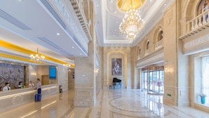 A spacious lobby with a grand chandelier, a reception desk, and a piano. - Vienna International Hotel (Wuhan)