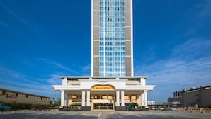 A tall hotel with a modern design, featuring a prominent entrance with columns and a large sign. - Vienna International Hotel (Wuhan)