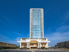 Un hotel alt amb un disseny modern, que destaca per una entrada imponent amb columnes i un gran rètol.