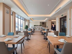 Un comedor moderno con mesas y sillas, una recepción y un ventanal grande.