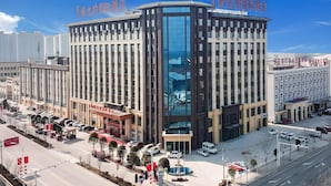 A multi-story hotel with a modern architectural design, featuring a prominent glass facade and a series of balconies. - Vienna International Hotel (Shangqiu)