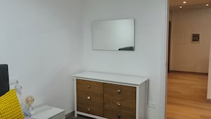 Quarto com cama, penteadeira, espelho e luminária no teto.