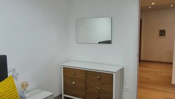 Ein Schlafzimmer mit Bett, Kommode, Spiegel und einer Deckenleuchte.
