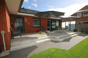 Eine Terrasse mit Tisch, Stühlen und Sonnenschirmen sowie einer Bank.