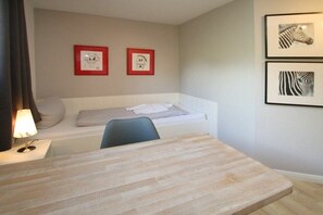 A small, single-room accommodation with a bed, a desk, and a chair. There are framed pictures on the wall. - Schmalstieg 11a, Wyker Perle (Wyk auf Föhr)