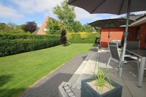 A patio area with a table and chairs, a potted plant, and a hedge. - Schmalstieg 11a, Wyker Perle (Wyk auf Föhr)