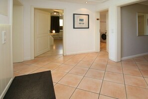 Ein Flur mit Fliesenboden, einem gerahmten Bild an der Wand und einer Tür zu einem Waschraum.