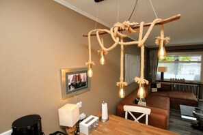 A cozy room with a wooden dining table, a brown sofa, and a unique rope chandelier. - E2 "Nordmeer" at Feldstr. 18 (Wyk auf Föhr)