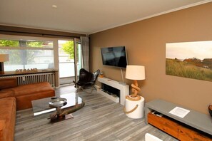 Een moderne woonkamer met een bank, salontafel, televisie en een open haard.