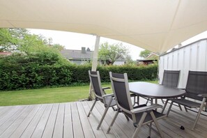 Eine Terrasse im Freien mit Tisch und Stühlen, umgeben von einer Holzterrasse und einem weißen Zaun.