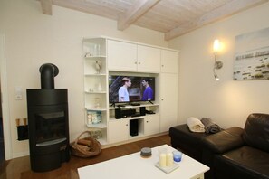 Ein Wohnzimmer mit Kamin, Fernseher, einer Couch und einem Couchtisch mit Kerzen.