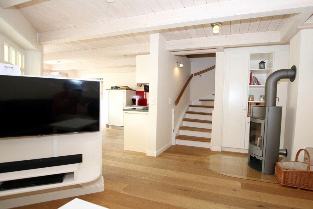 Un salon moderne doté d’un téléviseur à écran plat, d’une cheminée et d’un escalier menant à un espace cuisine.