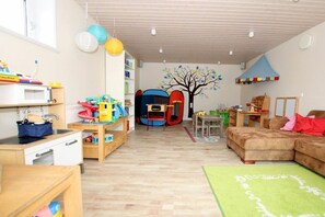 Un cuarto de juegos infantil con una alberca para bebé, juguetes y un mural de pared colorido.