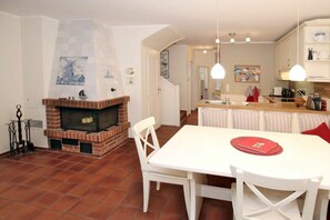 A kitchen with a brick fireplace, white dining table, and hanging pendant lights. - in the pastorate courtyard, house 3 in Ohl Dörp 22 (Wrixum)