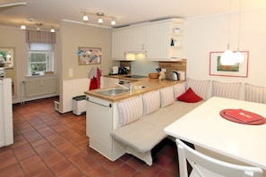 A compact kitchen with a dining area, white cabinetry, and a tiled floor. - in the pastorate courtyard, house 3 in Ohl Dörp 22 (Wrixum)
