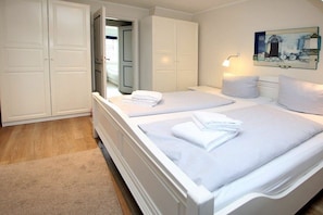 A hotel room with two beds, a wardrobe, and a painting on the wall. - in the pastorate courtyard, house 3 in Ohl Dörp 22 (Wrixum)