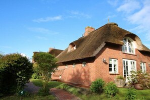 A traditional brick house with a thatched roof, a brick pathway, and a well-maintained garden. - in the pastorate courtyard, house 3 in Ohl Dörp 22 (Wrixum)