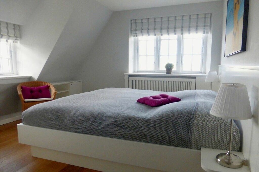 A bedroom with a bed, a chair, a window, and a radiator.