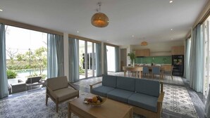 A modern living room with a sofa, coffee table, and dining area. - Cocoland River Beach Resort and Spa (Tu Nghia)