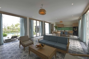 A modern living room with a sofa, coffee table, and dining area. - Cocoland River Beach Resort and Spa (Tu Nghia)