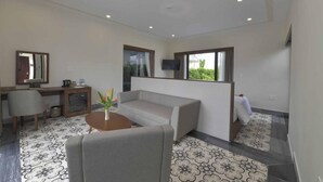 A modern living room with a sofa, a coffee table, and a TV mounted on the wall. - Cocoland River Beach Resort and Spa (Tu Nghia)
