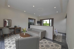 A modern living room with a sofa, a coffee table, and a TV mounted on the wall. - Cocoland River Beach Resort and Spa (Tu Nghia)