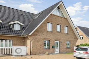 Ein zweistöckiges Haus mit geneigtem Dach, einer Ziegelaußenwand und einer weißen Tür.