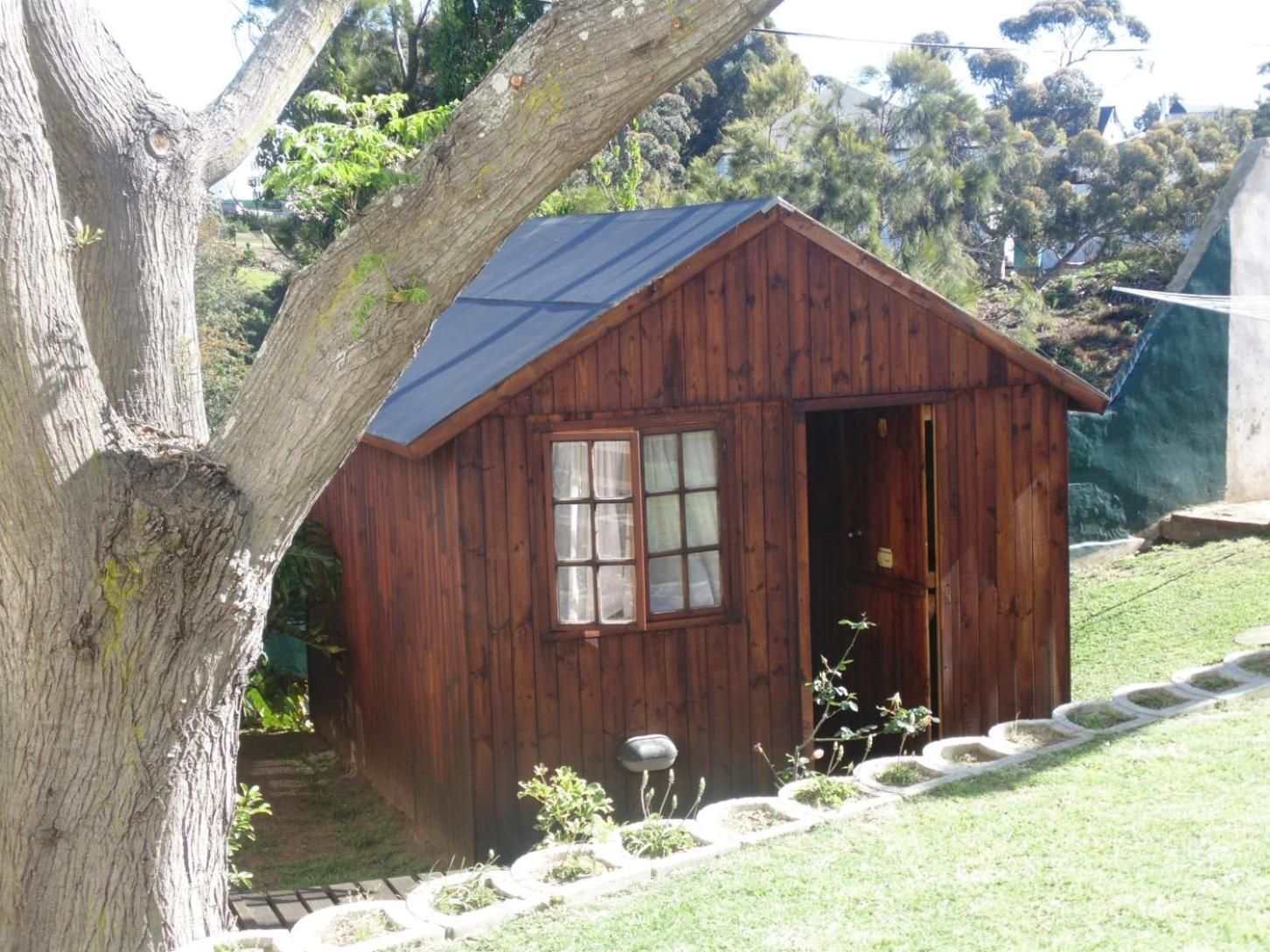 A wooden cabin with a pitched roof, a visible door, and a window with curtains.