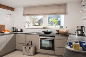 A modern kitchen with a built-in oven, a window with a view, and a coffee maker. - Holiday home with 4 bedrooms (St. Peter-Ording)