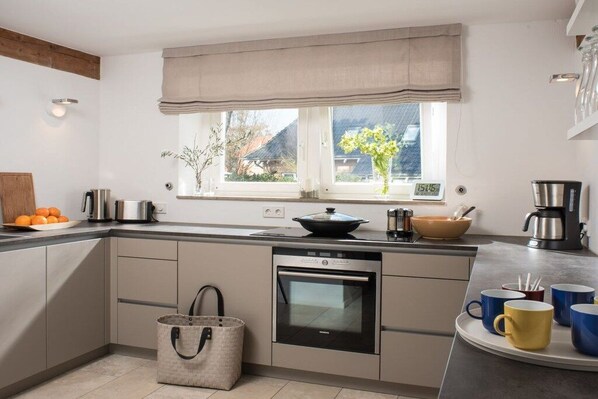 Una cocina moderna con horno empotrado, ventana con vistas y cafetera.