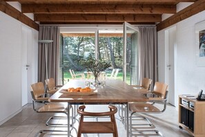 Een eetgedeelte met een houten tafel, stoelen en uitzicht op de omgeving.