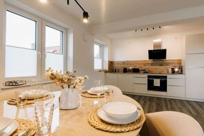 A modern kitchen with white cabinets, a built-in oven, and a microwave. - Holiday apartment in Greetsiel with balcony (Greetsiel)