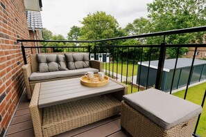 A balcony with wicker furniture, a table, and a tray with cups and a glass. - Holiday apartment in Greetsiel with balcony (Greetsiel)
