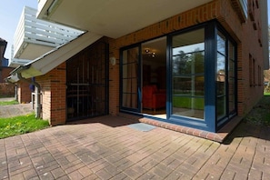 A brick building with a large glass door and a covered patio area. - Apartment 1 "Dune Dream" (ID 484) (St. Peter-Dorf)
