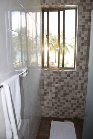 Casa de banho com janela, paredes azulejadas e um porta-toalhas.