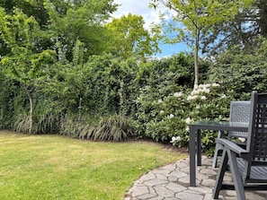 Ein Garten mit einem gepflasterten Weg, einem Tisch und Stühlen.