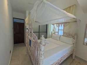 A four-poster bed with a canopy, a wooden headboard, and a large mirror on the wall. - Untold Stays Nyali Apartment (Mombasa)