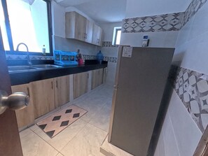 A kitchen with a refrigerator, a sink, and cabinets. - Untold Stays Nyali Apartment (Mombasa)