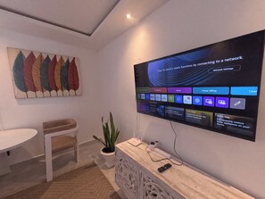 A modern room with a flat-screen TV mounted on the wall displaying a network settings screen. There is a white table and a potted plant in the room. - Untold Stays Nyali Apartment (Mombasa)