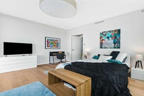 A modern bedroom with a bed, a TV, a desk, and artwork on the walls. - Holiday apartment with 1 bedroom (Olpenitz)