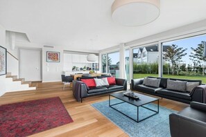 A modern living room with a black leather sofa, a coffee table, and a red rug. - Holiday apartment with 1 bedroom (Olpenitz)